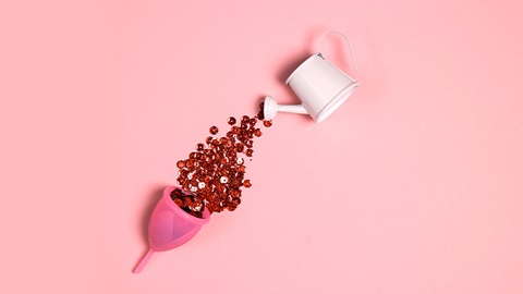 coppetta pestruale e annaffiatoio che versa liquido rosso